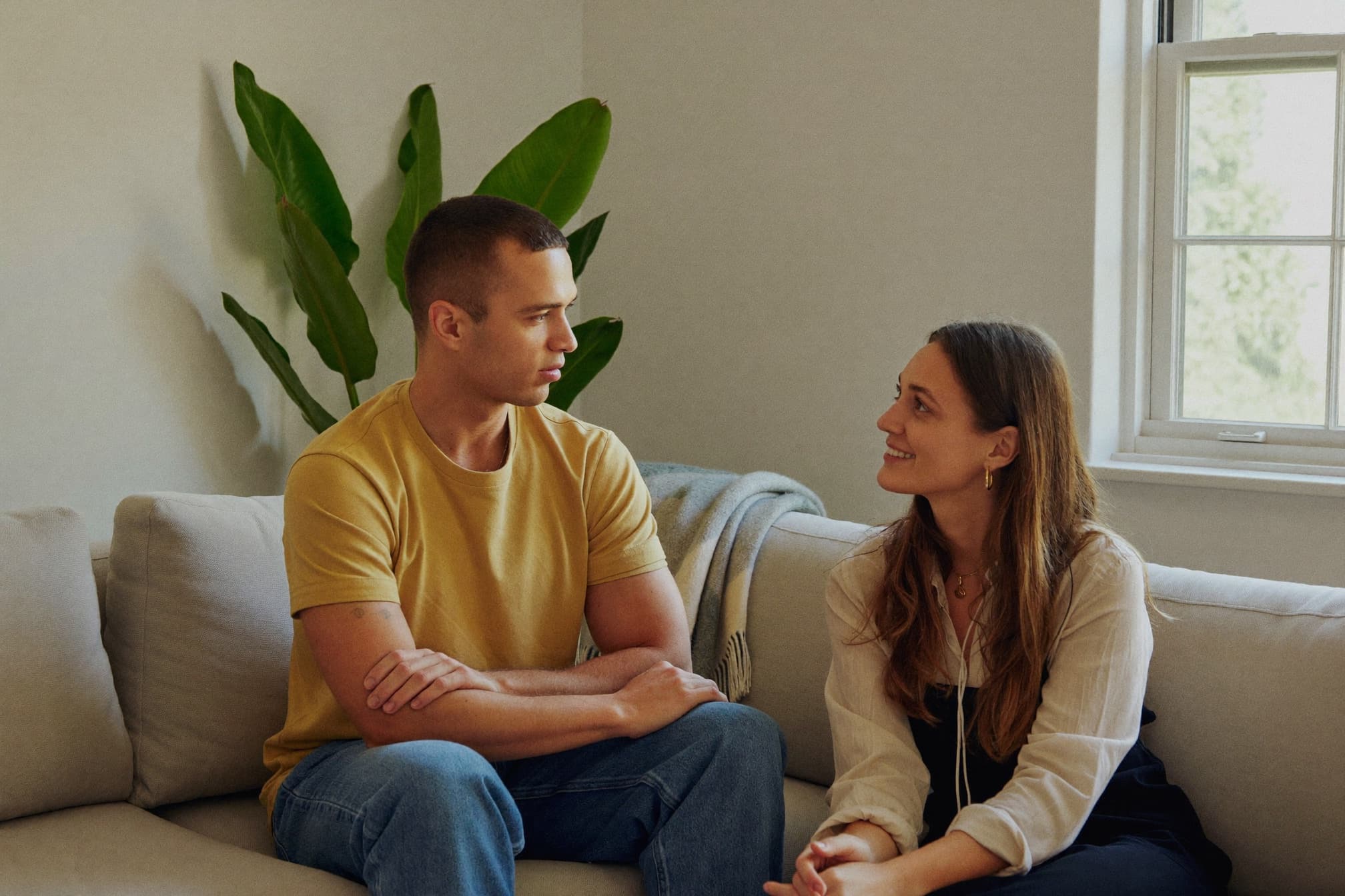 Two people sit together on a sofa, talking calmly