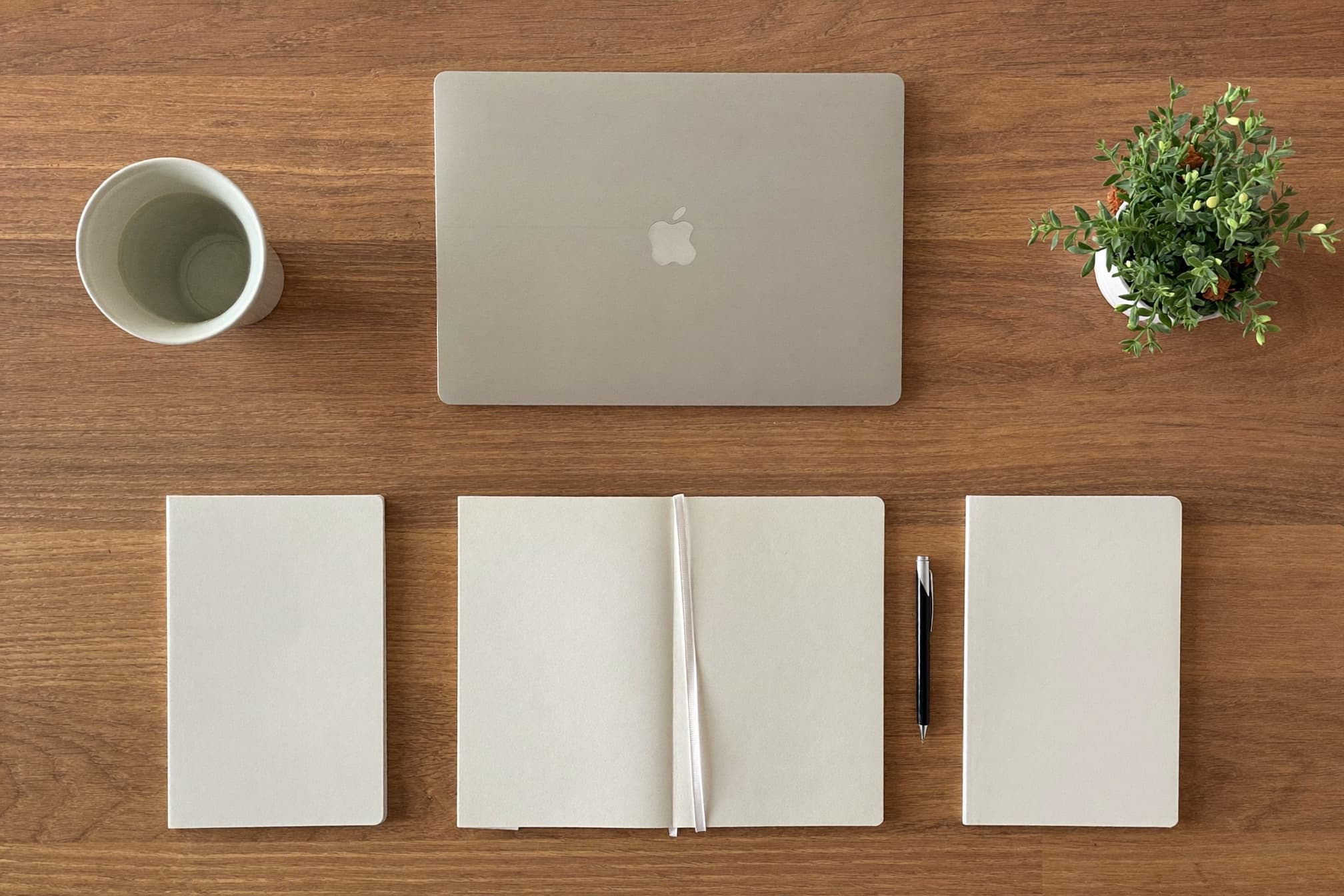 Overhead view of a tidy desk with a laptop and notebooks